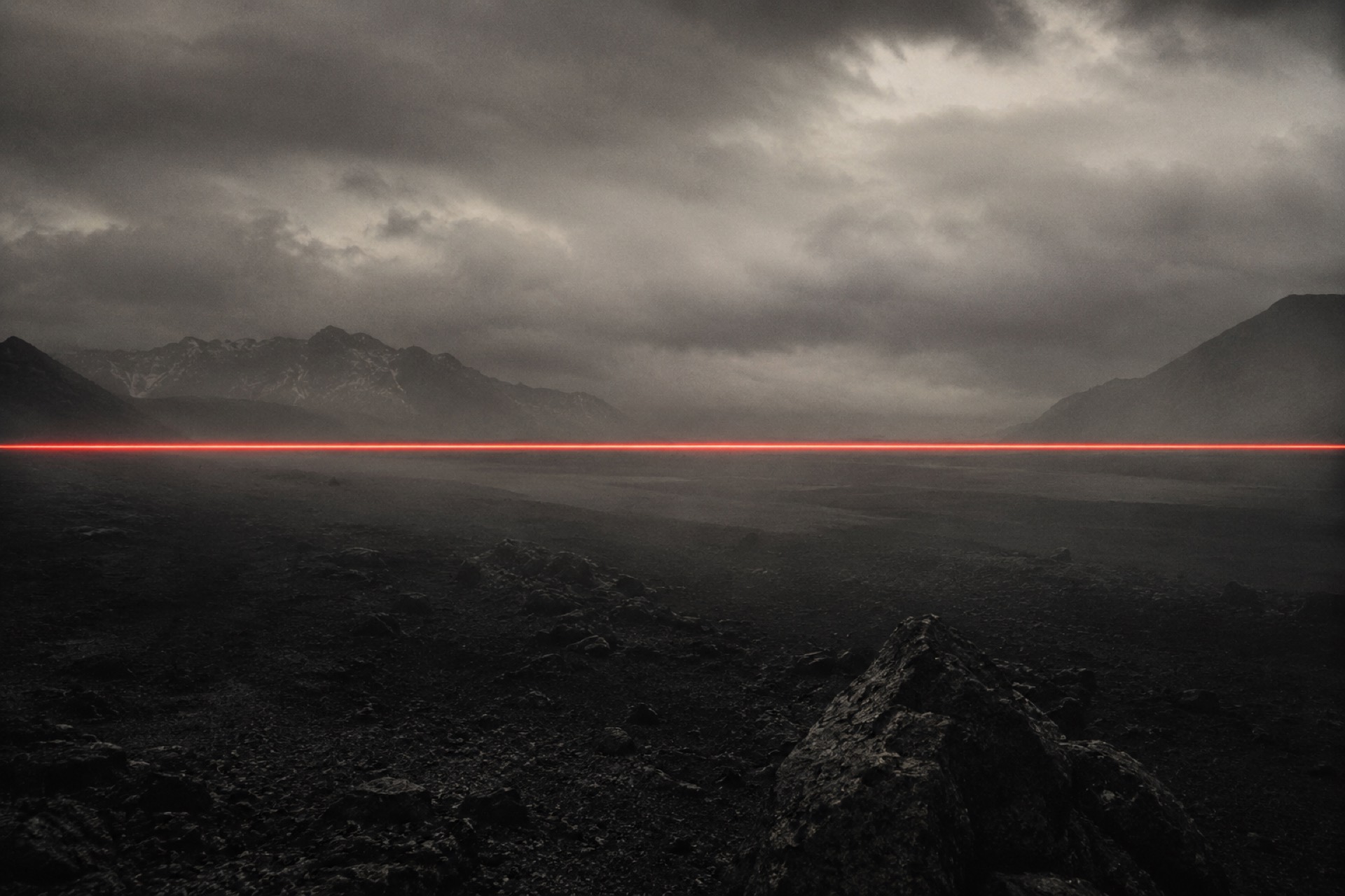 A thin red beam of light crossing a foggy horizon